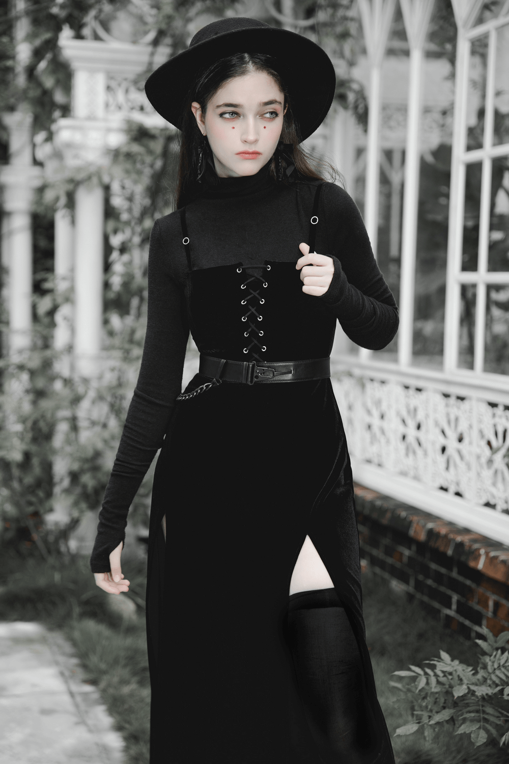 Gothic women's black velvet long dress with suspenders, showcasing punk style and a daring front slit.