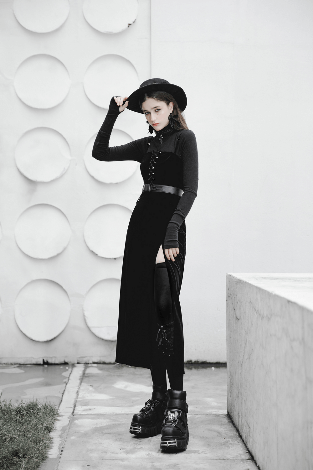 Gothic women's velvet long dress with suspenders, stylish punk look, showcasing black hat and platform shoes.