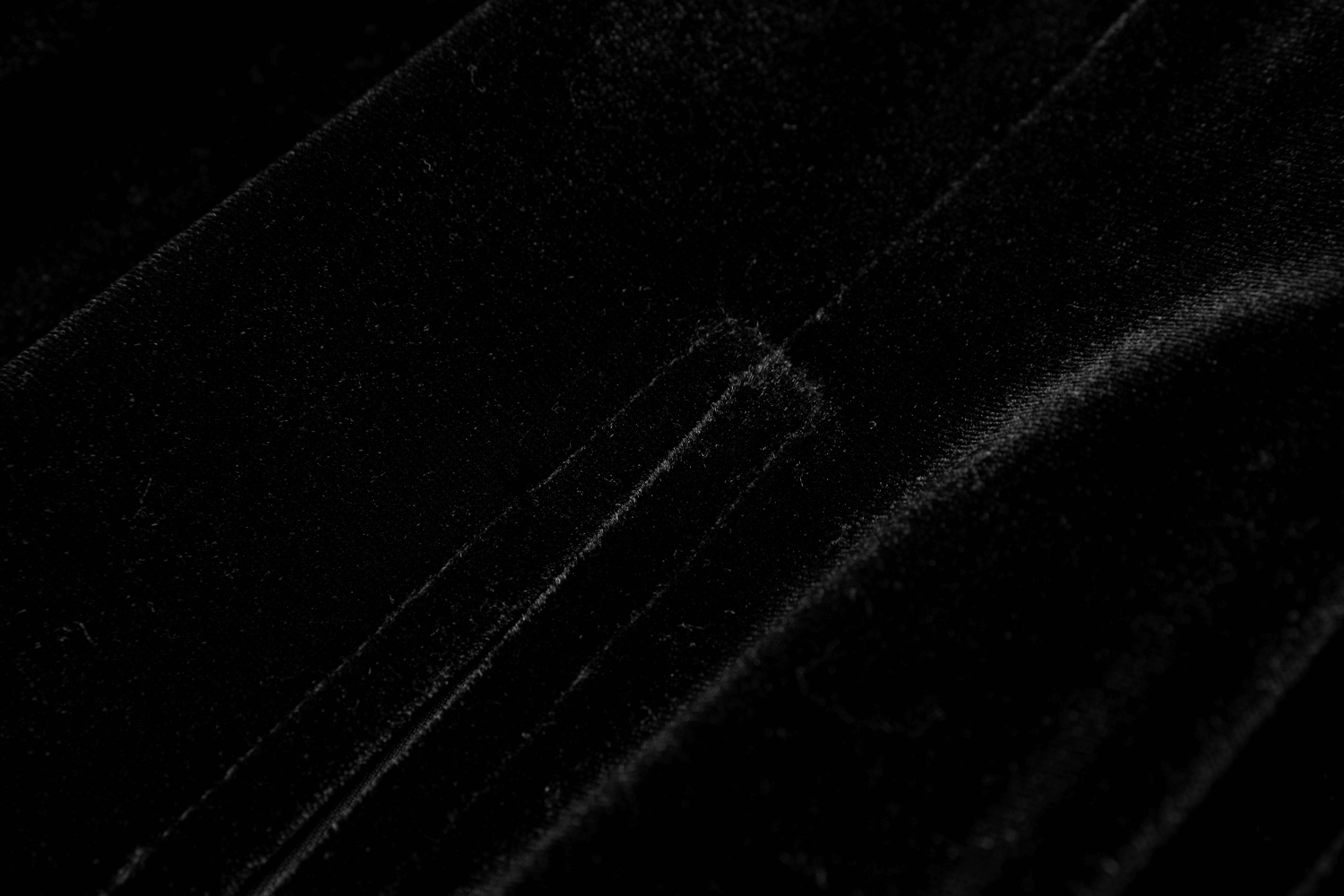 Close-up of luxurious black velvet fabric, showcasing its soft texture and rich color for a gothic dress.