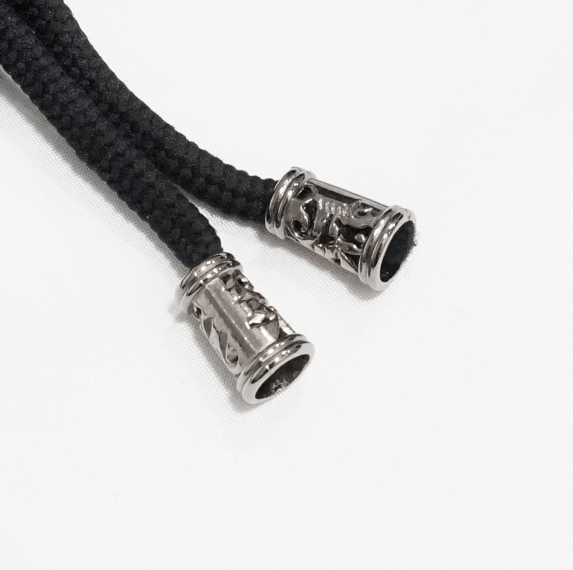 Close-up of black braided cord with ornate metal ends, perfect for gothic or alternative fashion accessories.