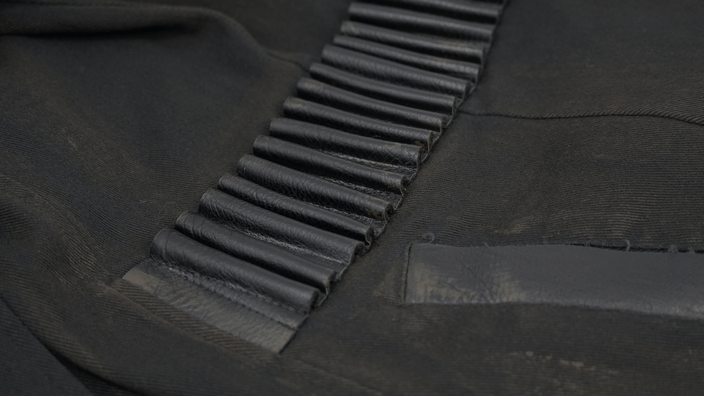 Close-up of the textured detailing on a gothic zipper hooded trench coat with buckles in black.