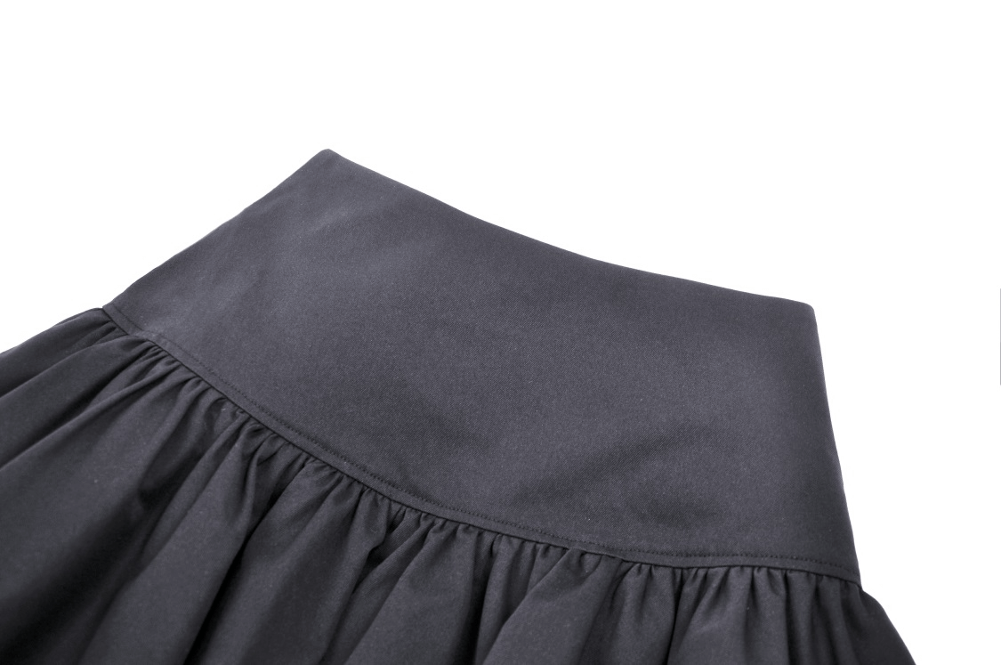 Close-up of the waistband and pleats of a gothic black mini skirt, perfect for edgy fashion lovers.