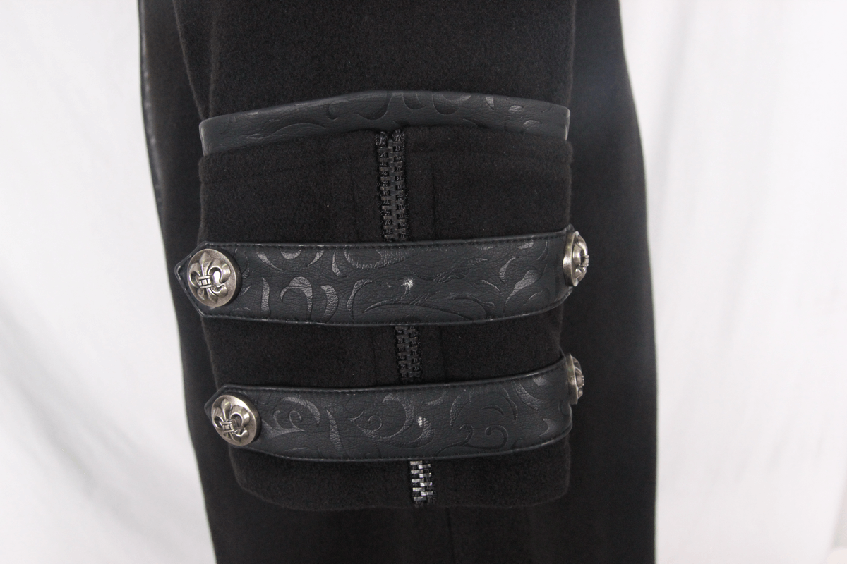 Close-up of gothic black trench coat sleeve with decorative buckles and intricate fabric pattern.