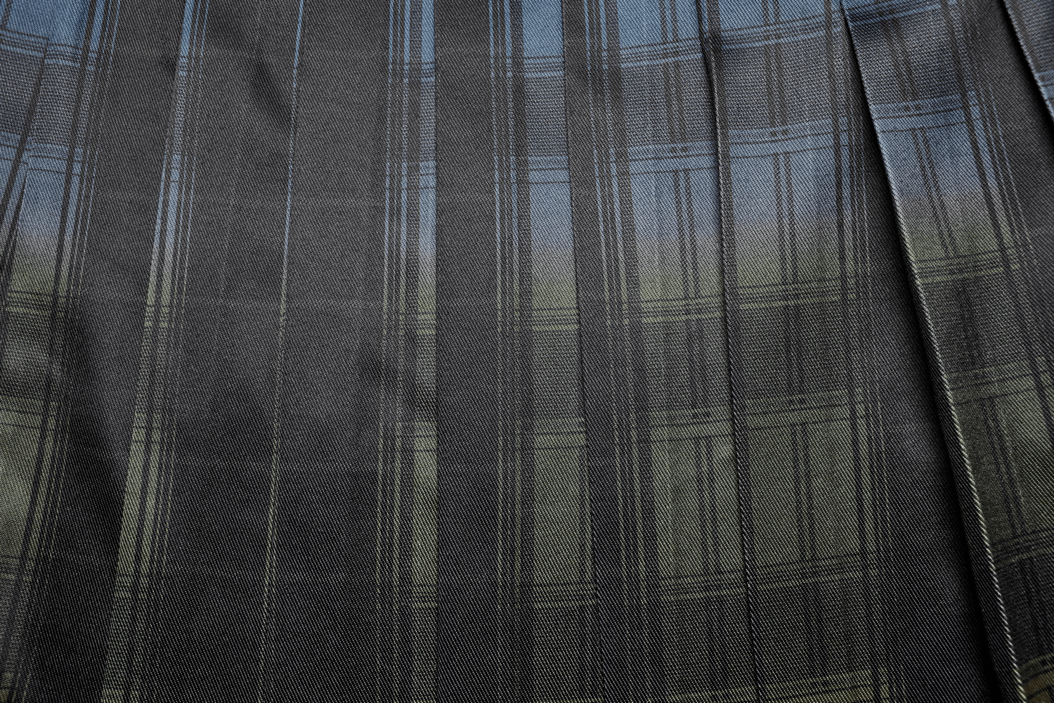 Close-up of black plaid pattern on a Scottish punk kilt, showcasing its unique gradient design and pleated detail.