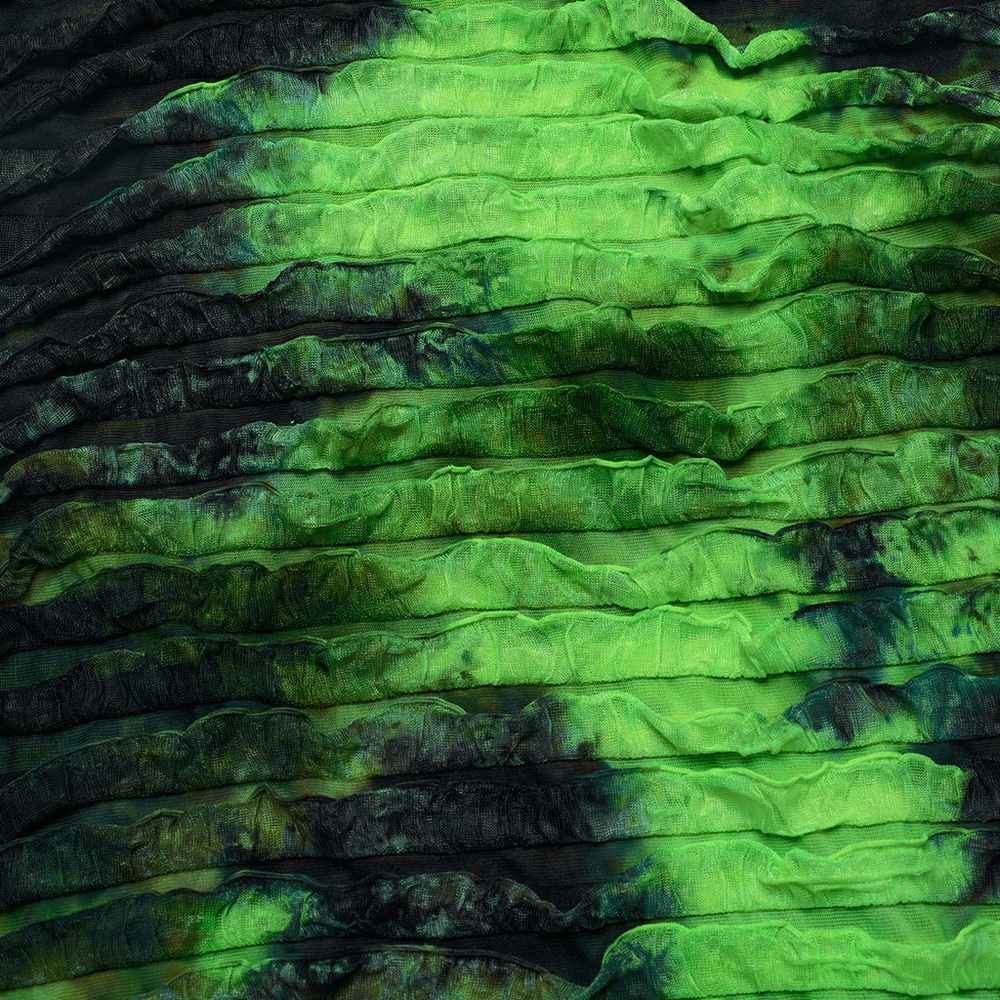 Close-up of green and black tie dye fabric with ruffled texture, perfect for stylish dress designs.