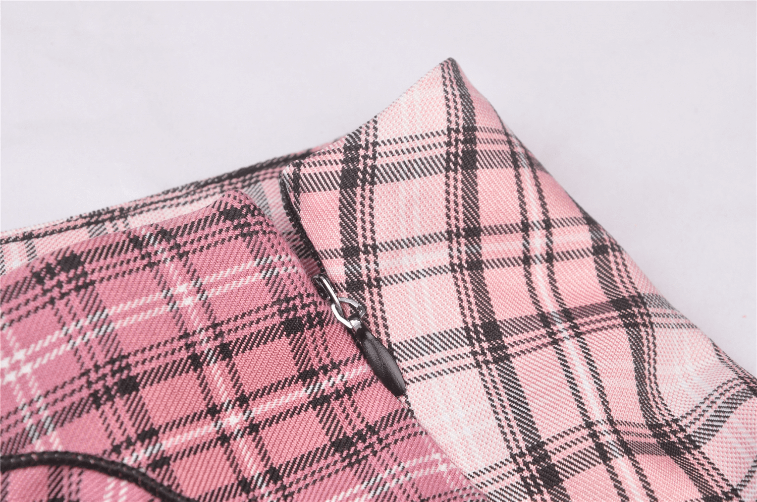 Grunge female mini skirt close-up featuring pink and black plaid pattern and zipper detail.