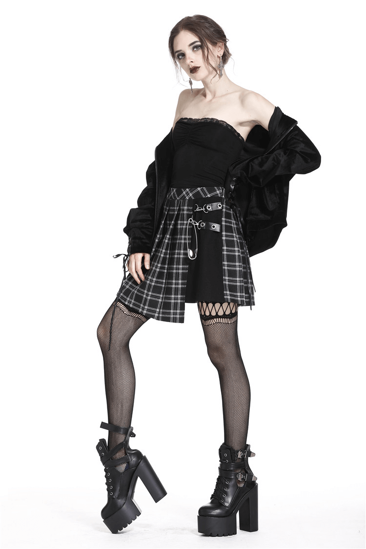 Grunge gothic model wearing an asymmetrical plaid mini skirt with chunky safety pins and platform boots.