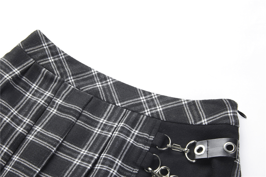 Close-up of a grunge gothic asymmetrical plaid skirt featuring silver safety pin accents.