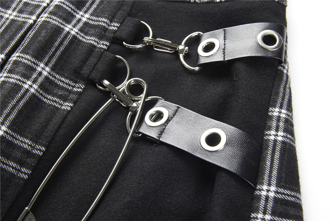 Close-up of grunge gothic asymmetrical plaid skirt with large silver safety pin and eyelets.