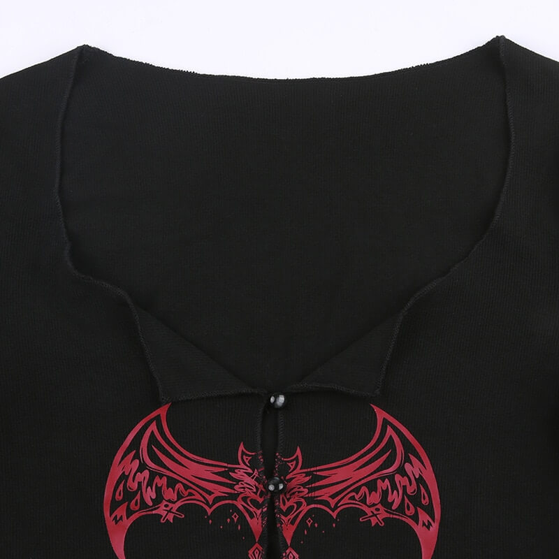 Close-up of a black grunge top with red dragon graphic and button detail, perfect for gothic fashion lovers.