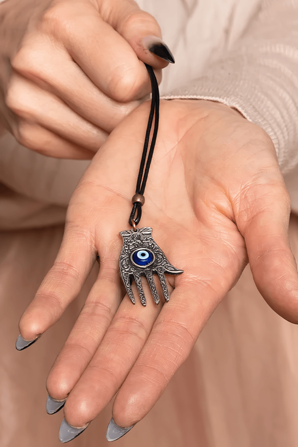 Hamsa Hand Pewter Protection Amulet Pendant Charm held in hand, featuring an evil eye bead for protection.
