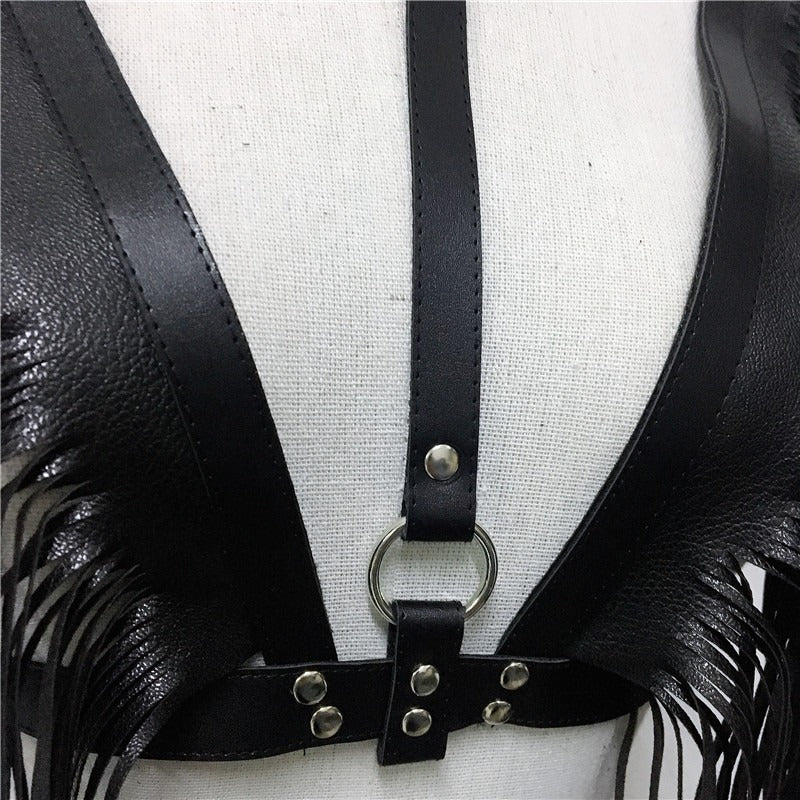 Close-up of a black leather crop top with decorative fringes and metal accents, ideal for goth and rave outfits.