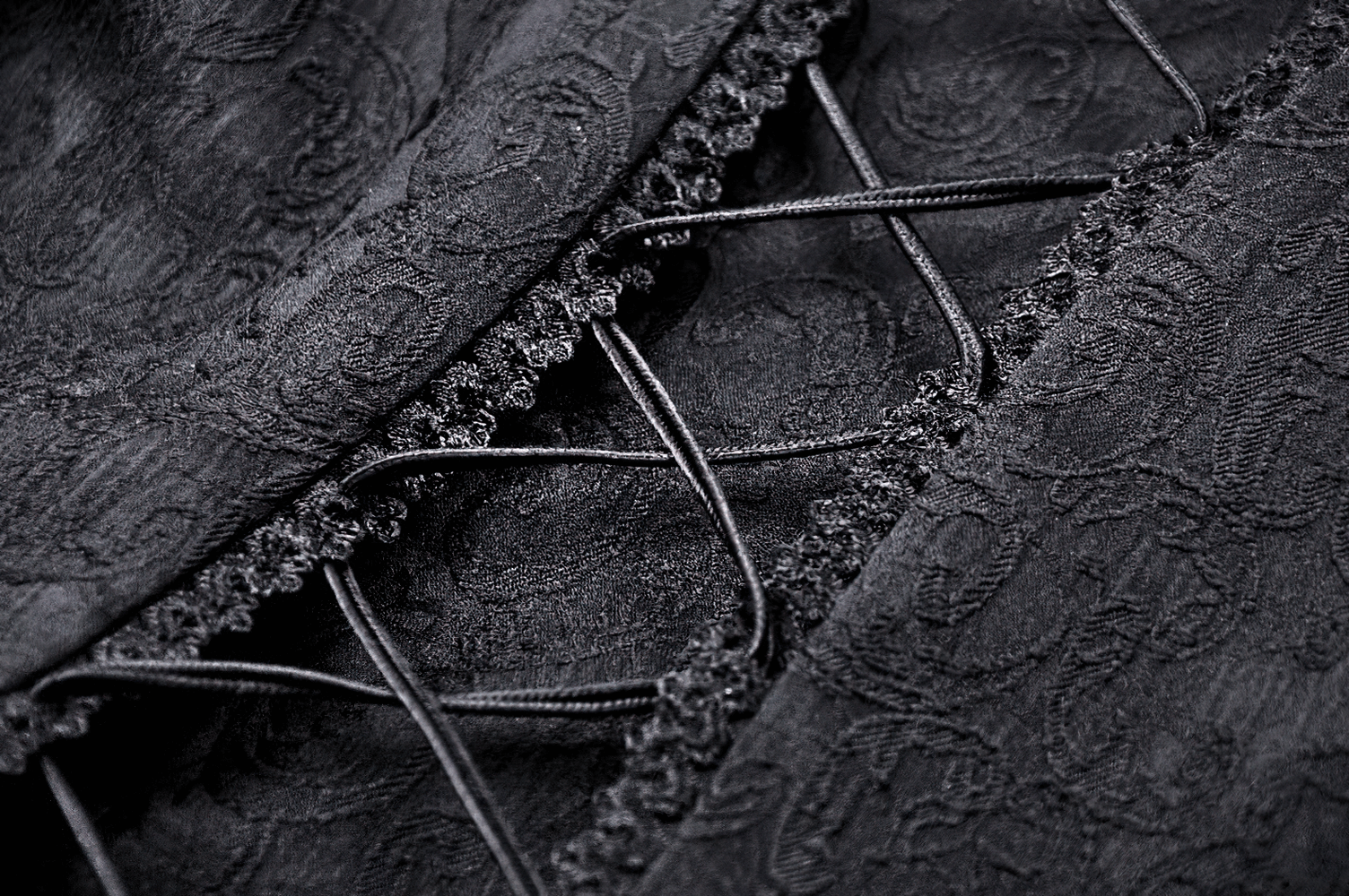 Close-up of black lace fabric with intricate corset lacing details, perfect for gothic fashion.