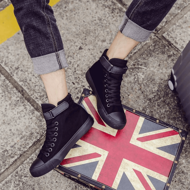 Black high top sneakers on a vintage Union Jack suitcase, showcasing stylish lace-up design for trendy outfits.
