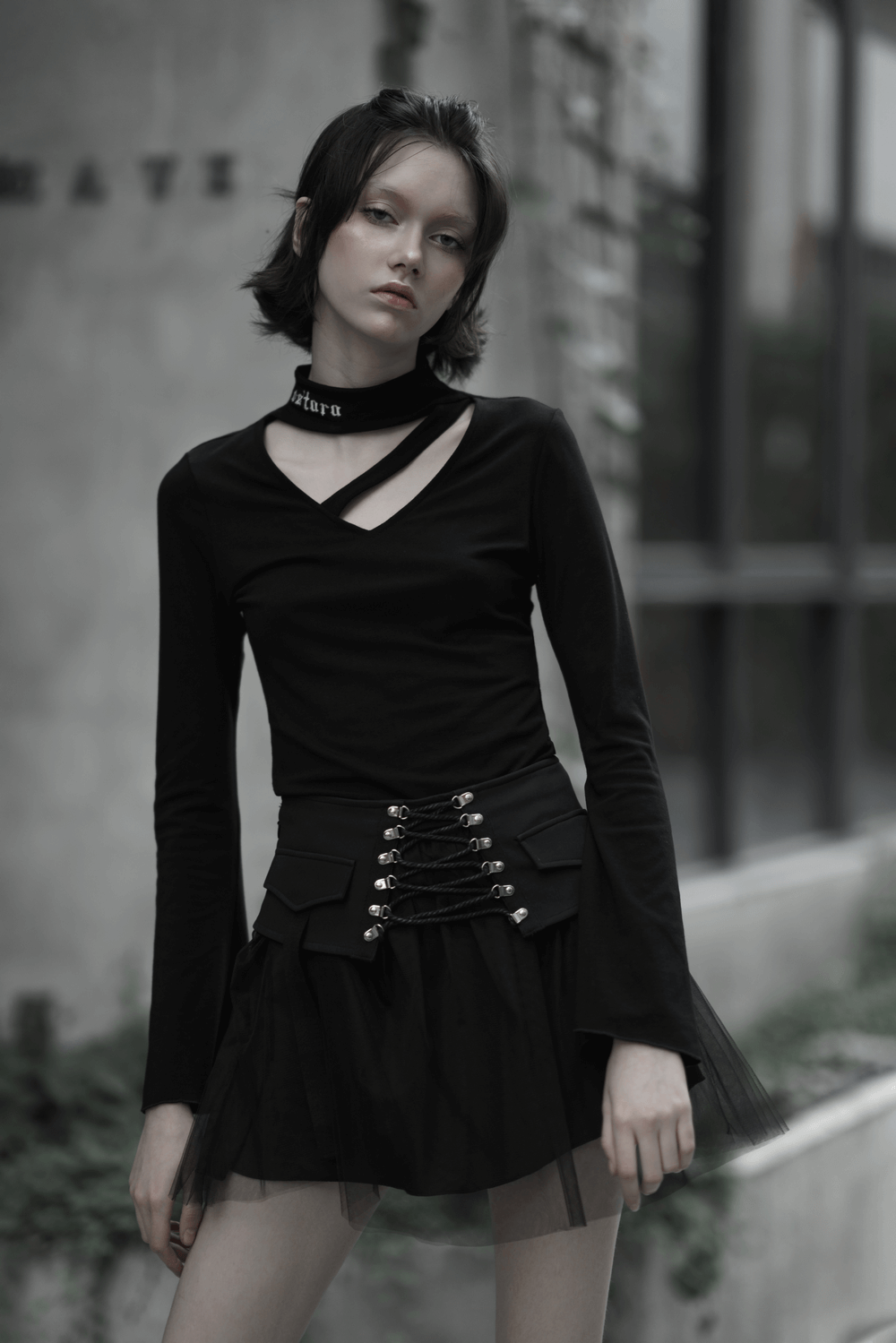 Model showcasing a high-waist black gothic skirt with lace-up detail and a stylish black top in an urban setting.