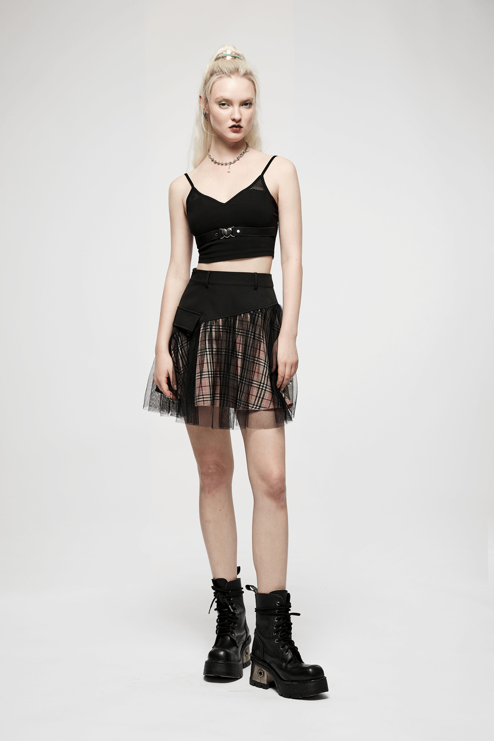 Model wearing a high-waisted pink plaid gothic mini skirt with mesh accents and chunky black boots.