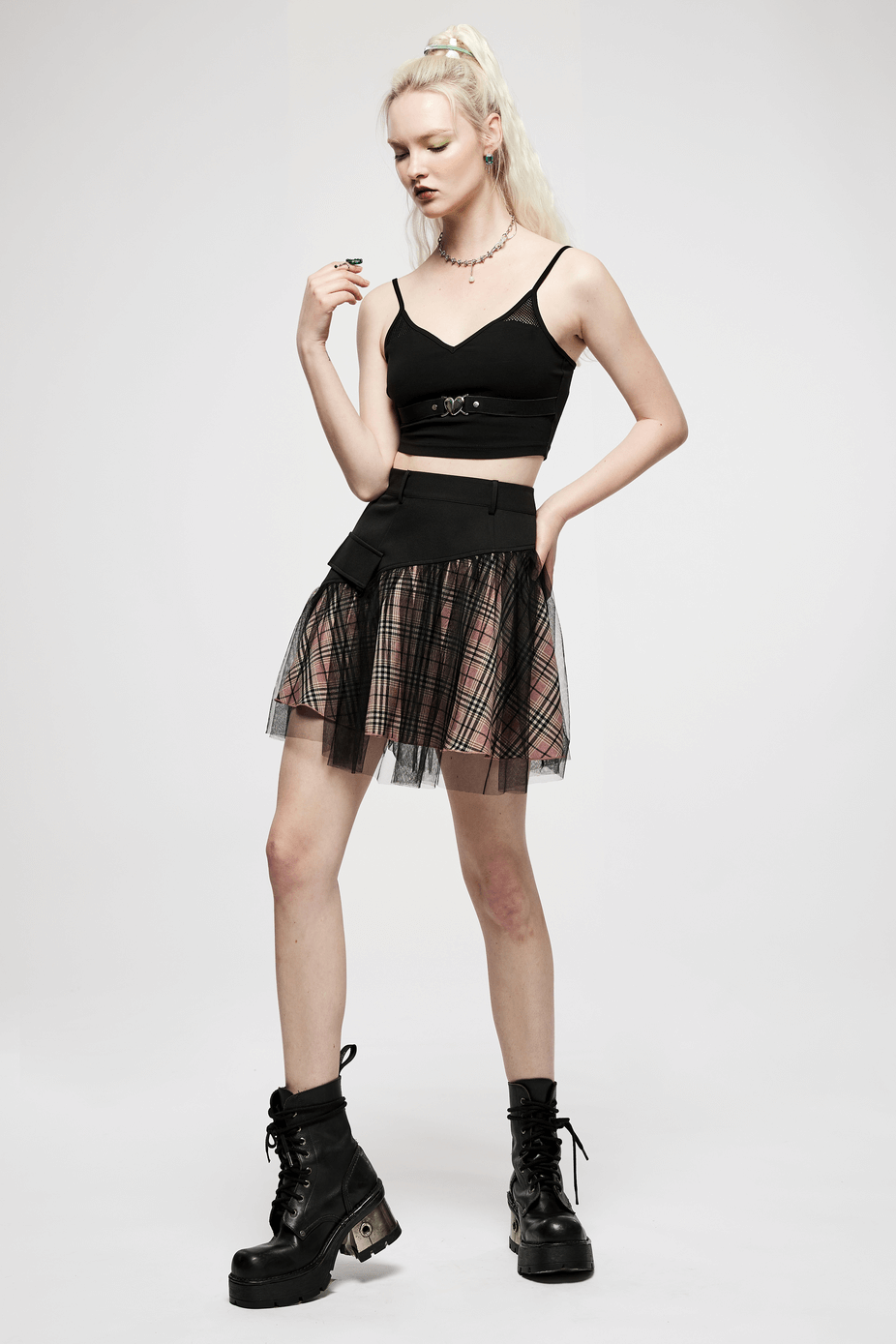 Model showcasing a high-waisted gothic mini skirt with pink plaid and edgy mesh accents.