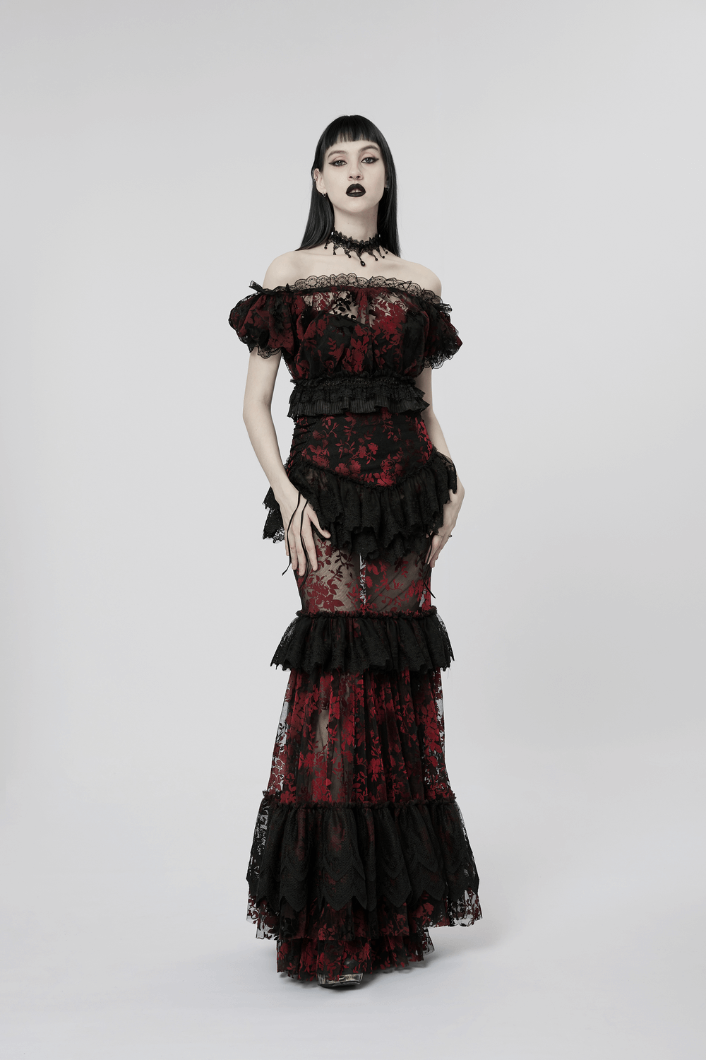 Victorian goth model in an elegant black and red lace gown with layered frills and off-shoulder design.