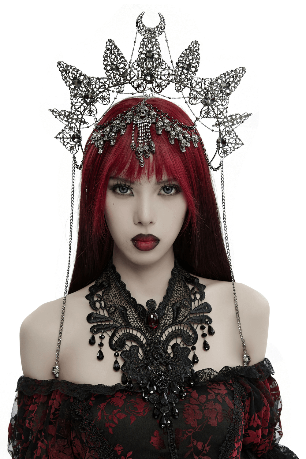 Gothic crown with skull pendants and chains, adorned with gemstones, worn by a model with red hair.