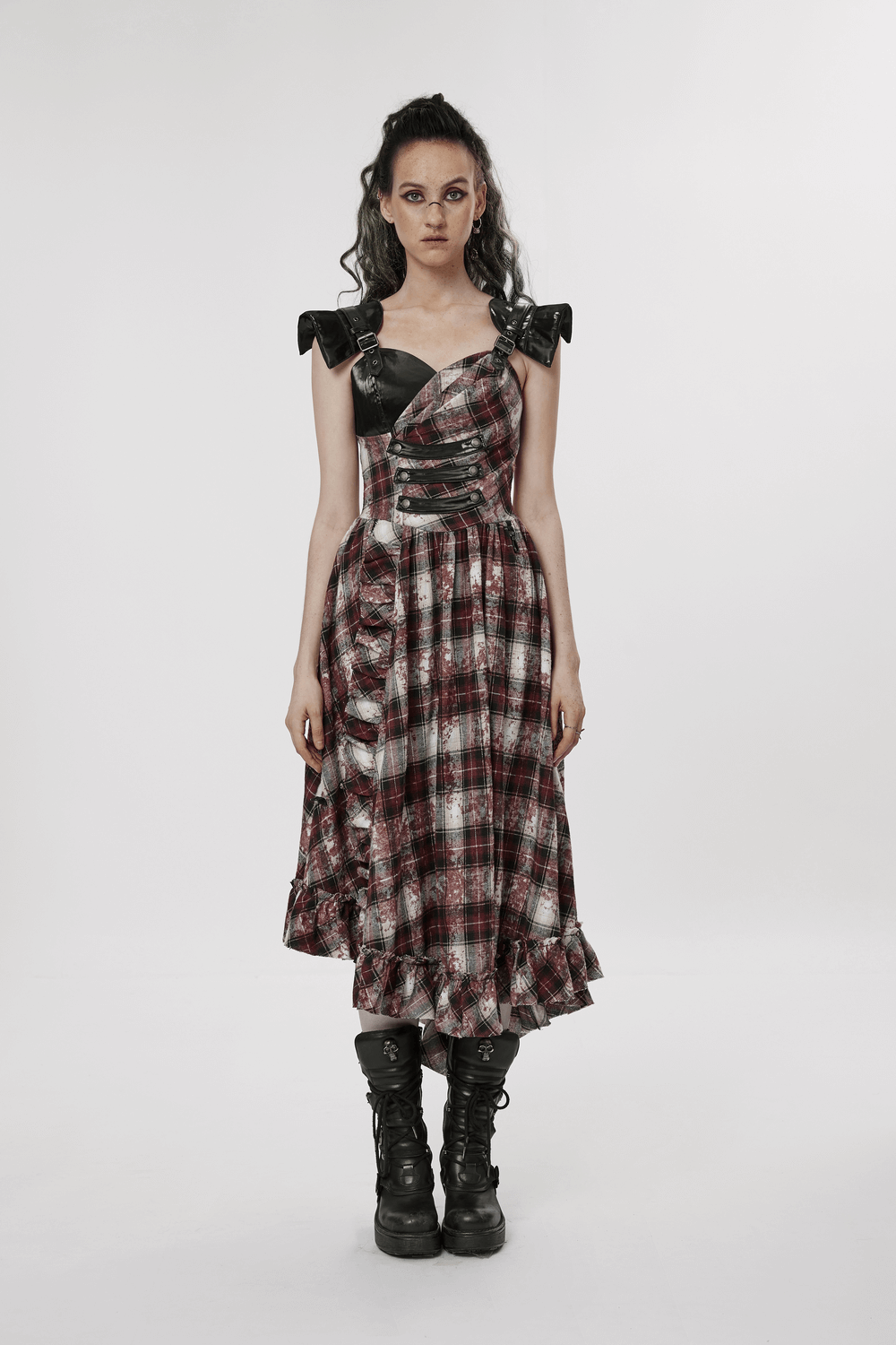 Punk rock model in an irregular hem plaid dress with adjustable leather straps and edgy style.
