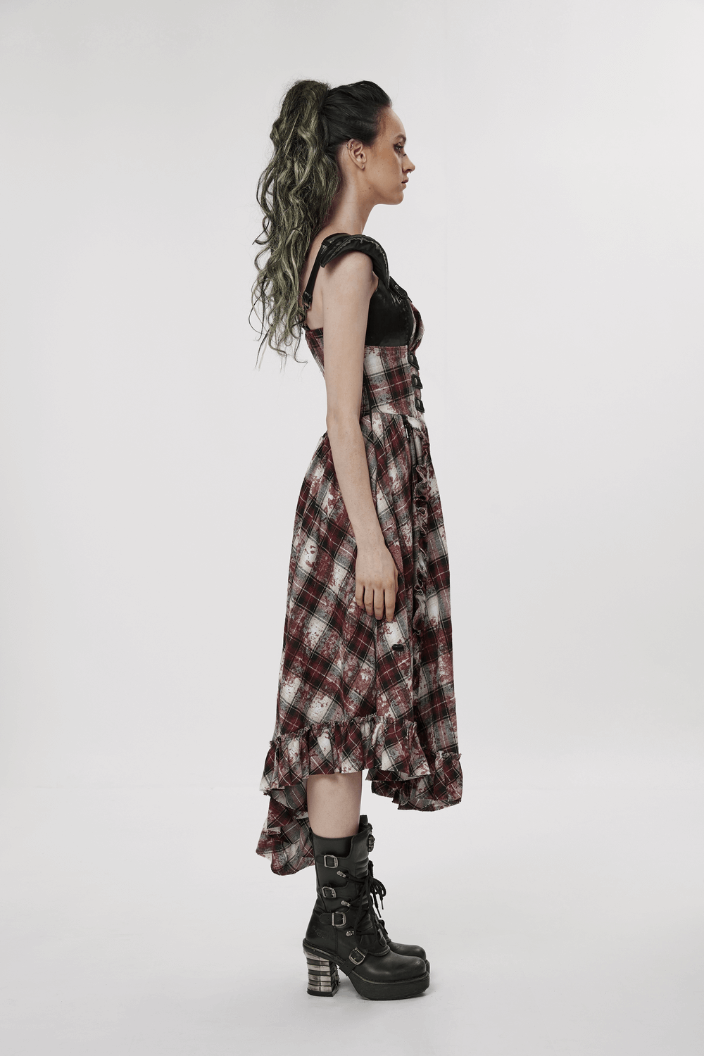 Punk girl in irregular hem plaid dress with adjustable straps and combat boots, showcasing edgy style.