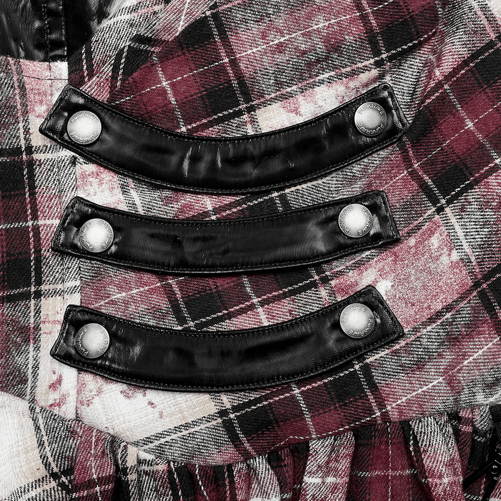 Close-up of adjustable faux leather straps and plaid pattern on irregular hem plaid dress.