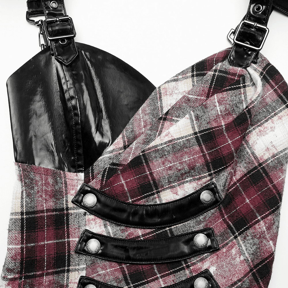 Close-up of an edgy plaid dress with adjustable leather straps and D-shaped clasps, showcasing its unique style.