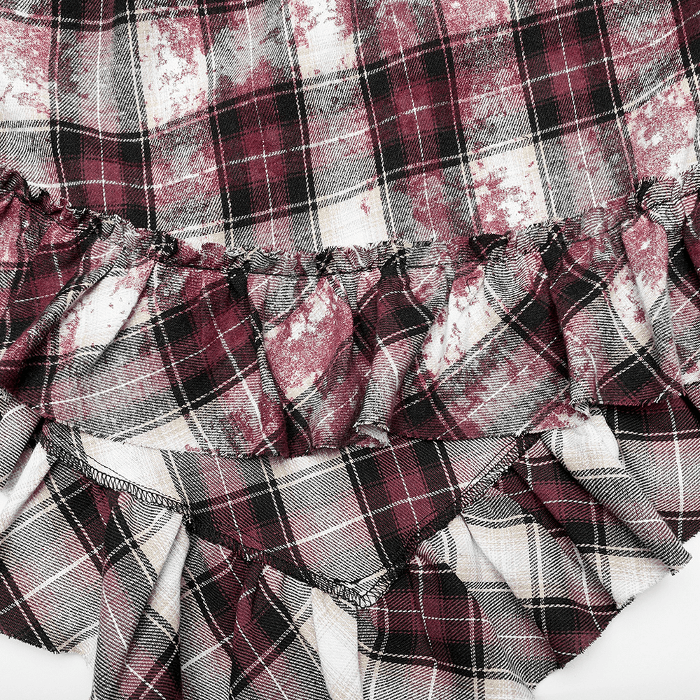 Close-up of irregular hem on a plaid dress with ruffles in burgundy and black, showcasing an edgy punk style.