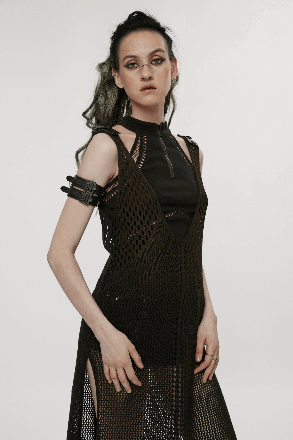 Model in a black knitted hollow techwear dress with edgy features, showcasing post-apocalyptic fashion style.