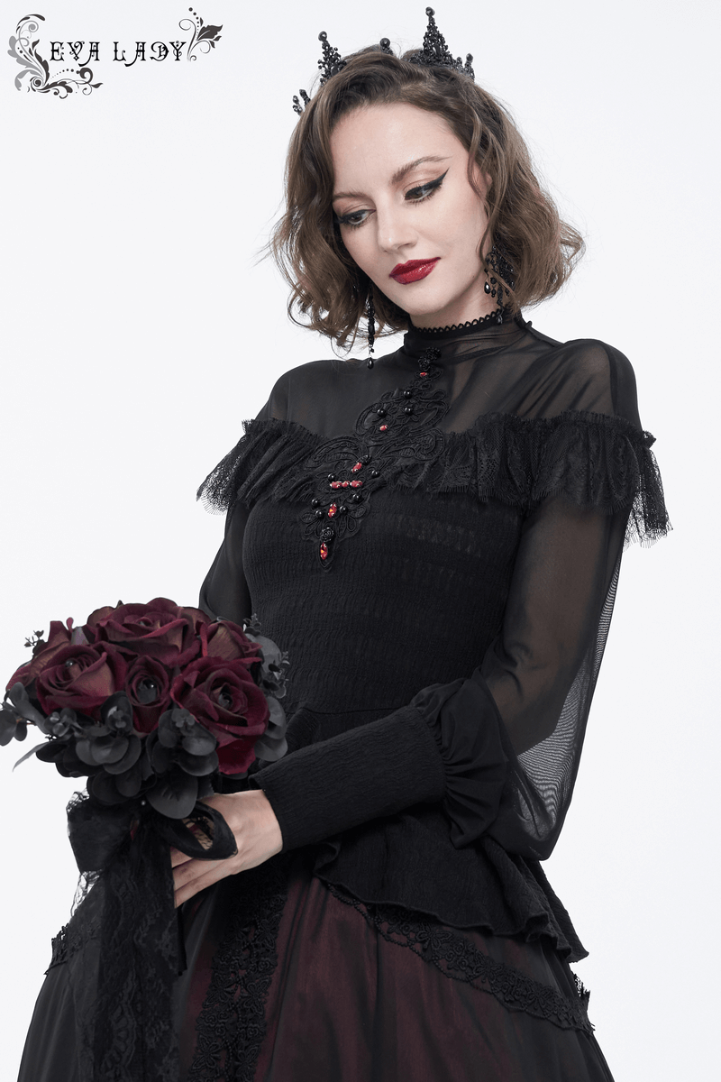 Stylish woman in a black lace appliqué beaded gothic blouse with transparent sleeves, holding a bouquet of dark roses.