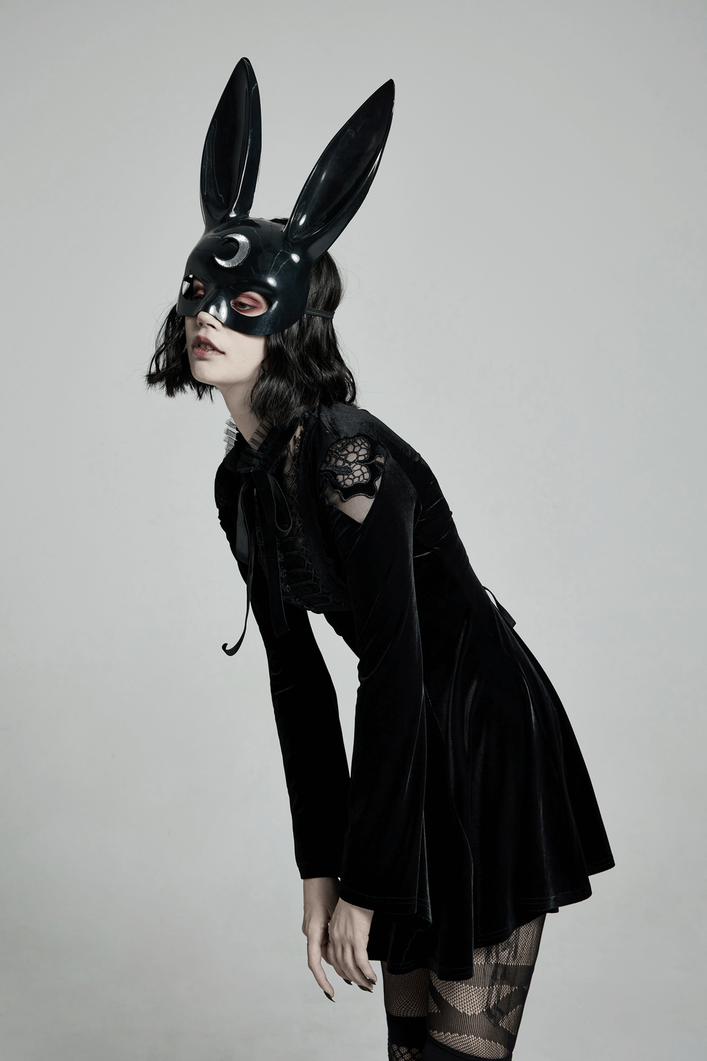 Gothic woman in a black velvet dress and bunny mask, showcasing a lace collar and punk-inspired style.