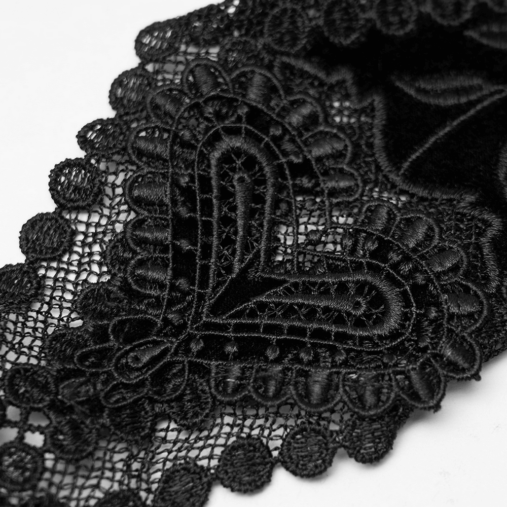 Close-up of elegant black lace featuring a heart decal, showcasing intricate gothic floral design.