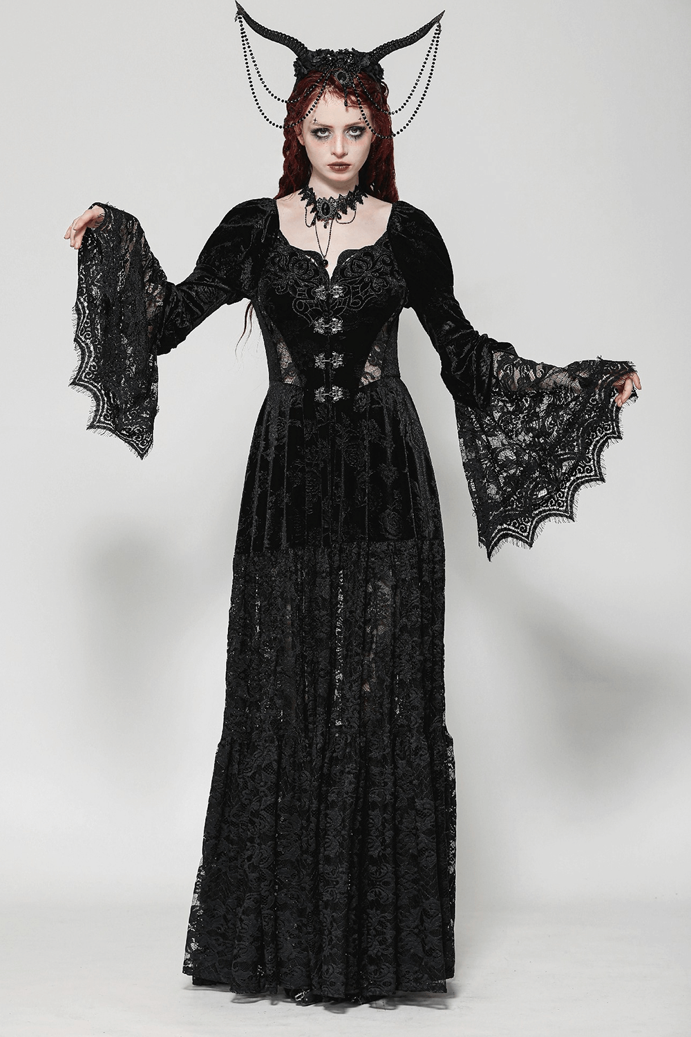 Elegant woman in black lace Gothic evening gown with floral accents and dramatic sleeves.