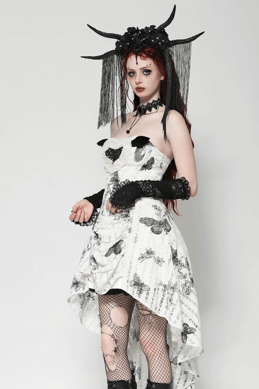 Gothic model wearing a black and white dress with lace gloves, showcasing an elegant, dark fashion look.