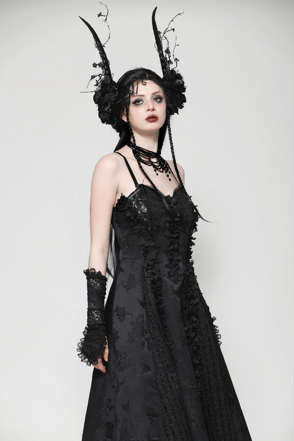 Gothic model wearing a stunning black dress with lace details, frilled gloves, and striking horns, perfect for a dark fashion look.