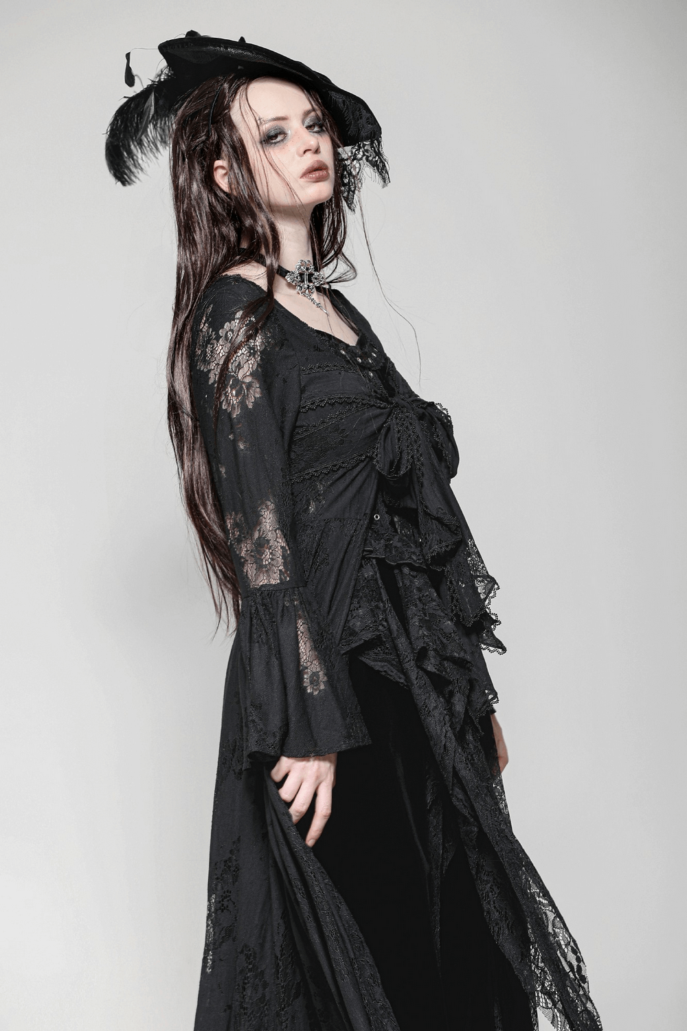 Elegant model in gothic lace cape with floral patterns and bow tie, showcasing vintage bell sleeves.