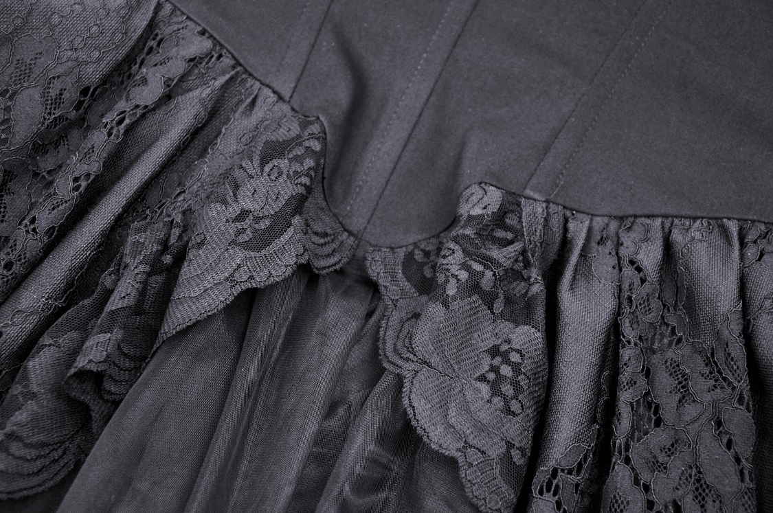 Close-up of black lace detailing on a gothic high-low dress, showcasing intricate lace patterns and layers.