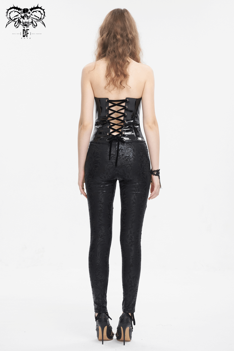 Back view of a woman in a lace patent leather corset with lace-up detail and fitted black pants.