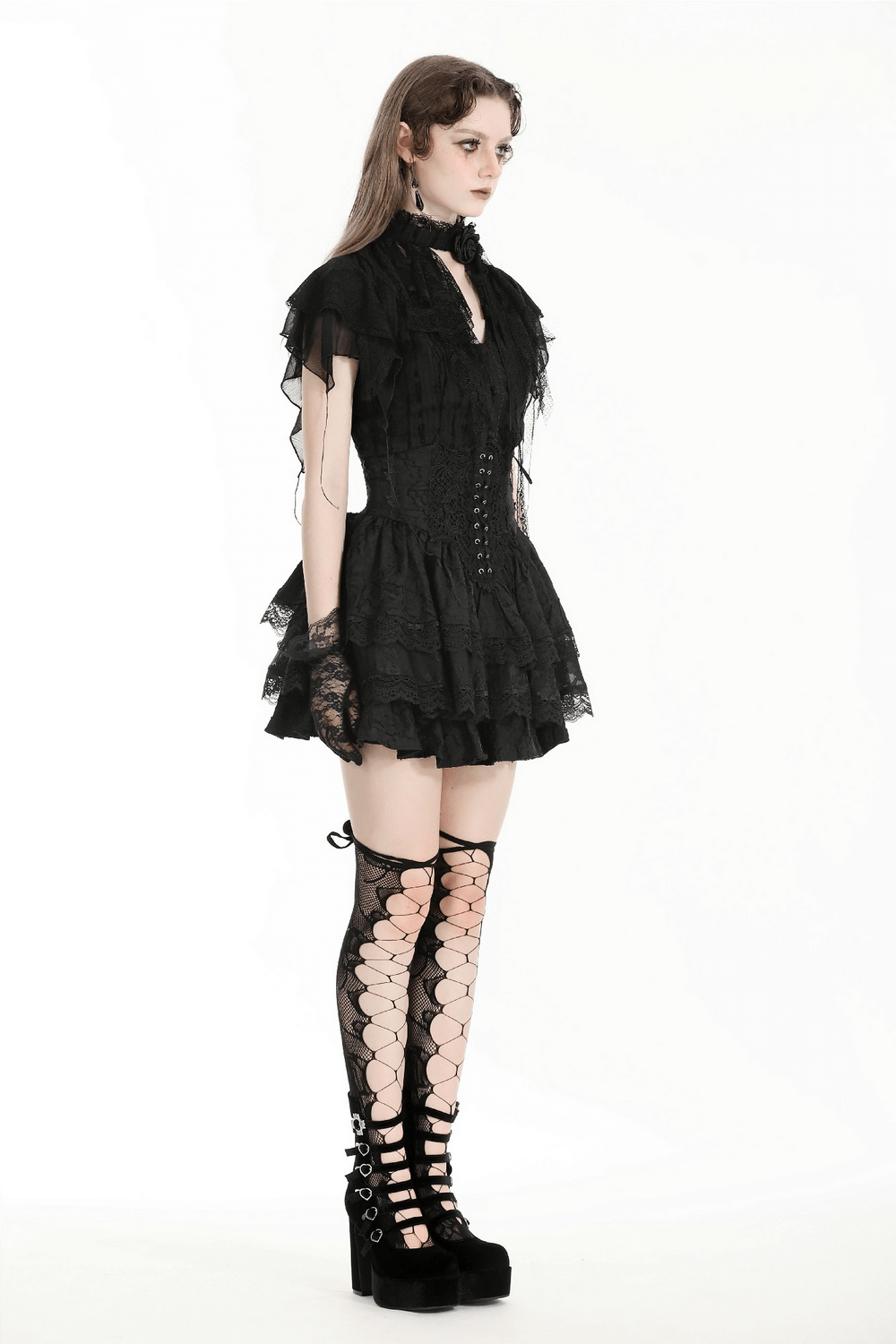 Model showcasing a Victorian inspired black lace dress with ruffled sleeves and striking lace-up knee-high socks.