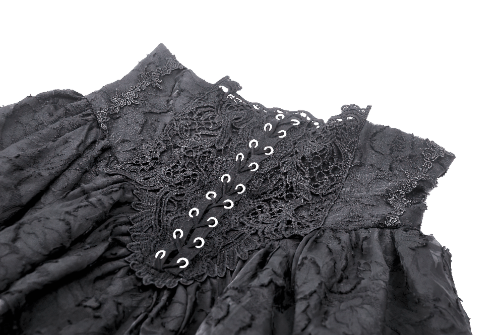 Close-up of lace trim detail on a gothic black layered skirt with decorative eyelets.