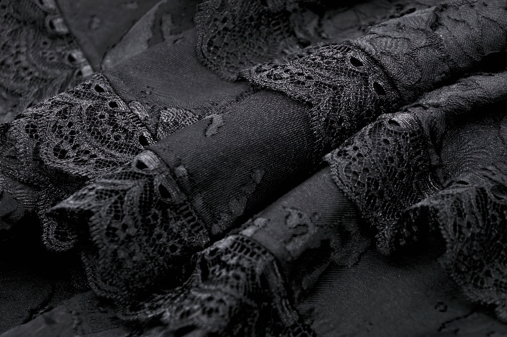 Close-up of elegant black lace trim, showcasing intricate details on gothic layered fabric.