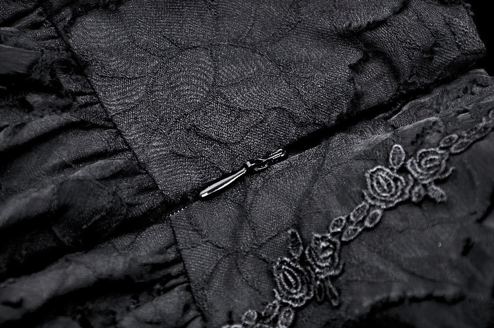 Close-up of lace and zipper detail on a black gothic layered skirt, showcasing intricate floral embroidery.