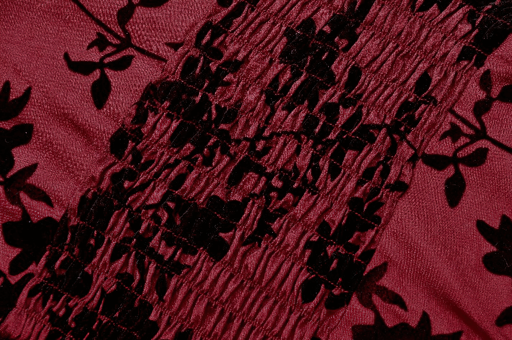 Close-up of rich burgundy fabric featuring floral lace detailing and elegant ruching texture.