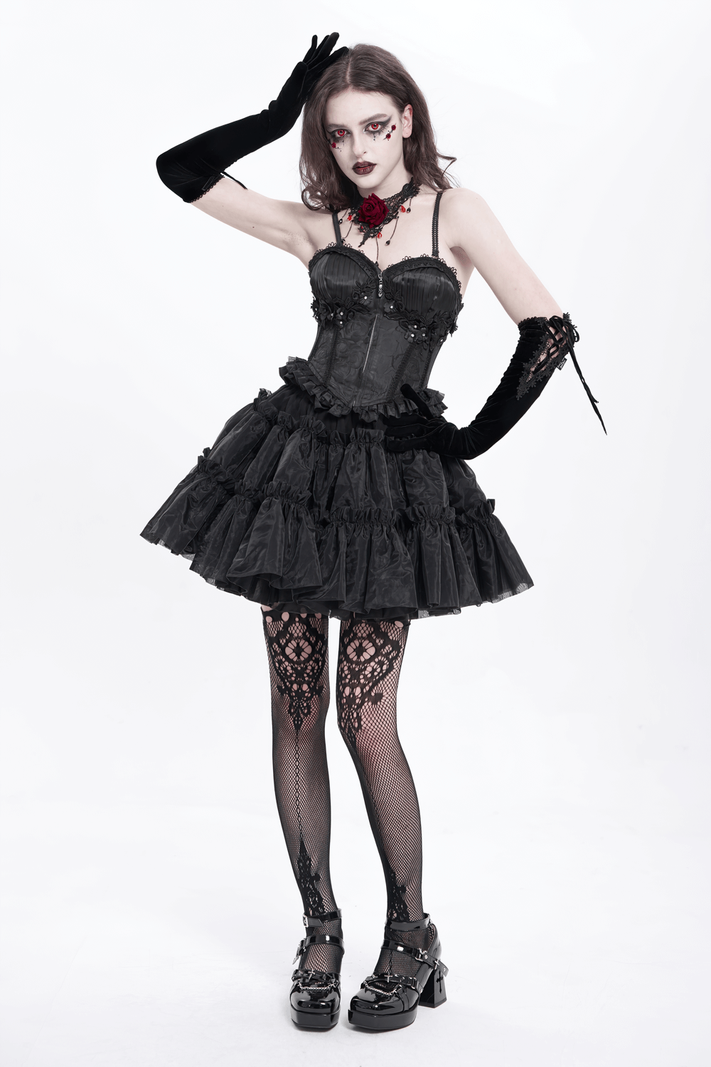 Gothic model wearing a black floral embellished corset dress with ruffles, black gloves, and lace stockings.