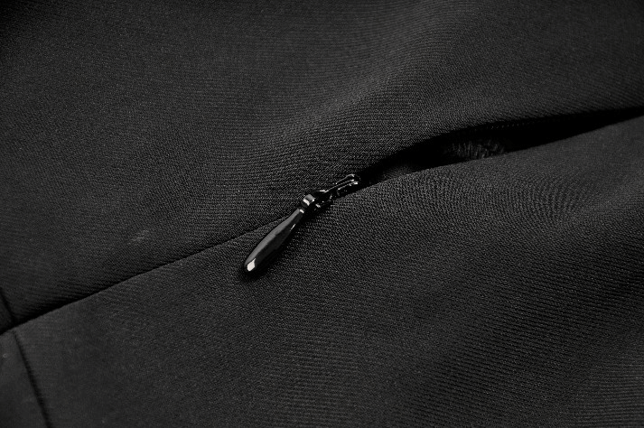 Close-up of a black zipper on fabric, showcasing detail and texture for stylish garment design.