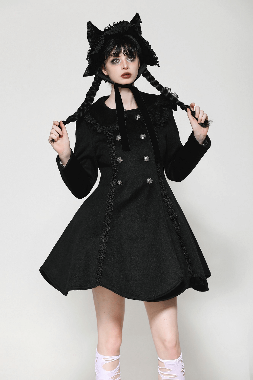 Elegant lady in a black Victorian-style buttoned coat with lace, sporting a playful cat-ear hat and braided hair.