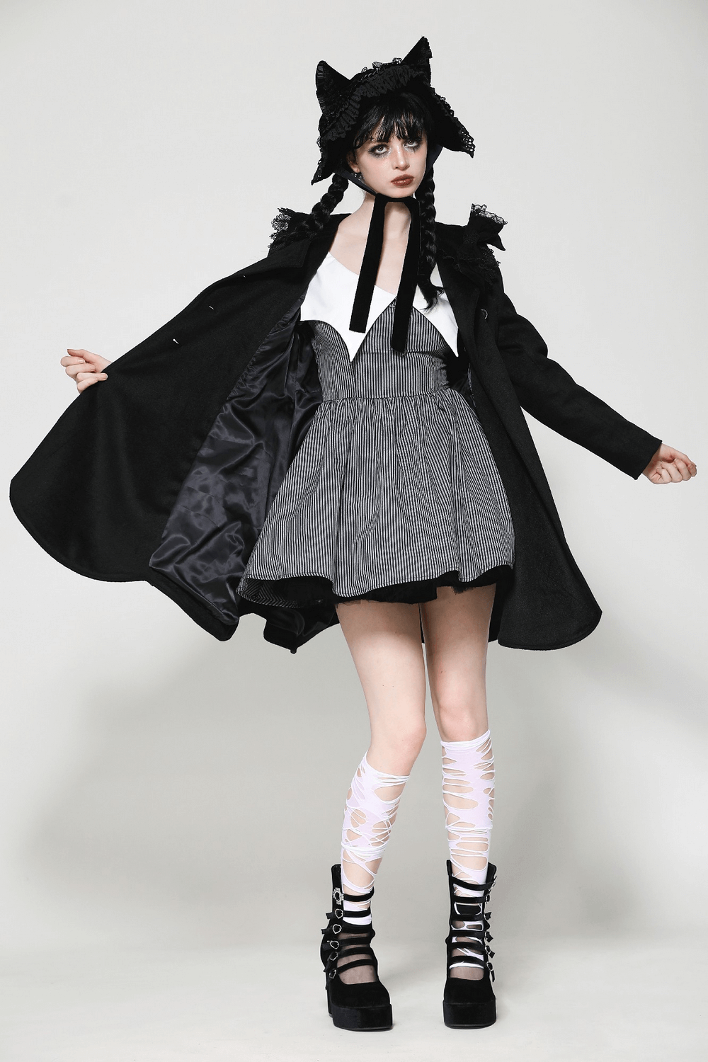 Stylish model showcasing a black Victorian coat with lace trim, paired with a playful outfit and knee-high stockings.