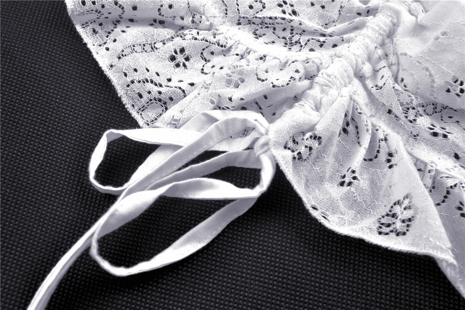 Close-up of lace detail and adjustable straps on a white lace midi dress for a gothic look.