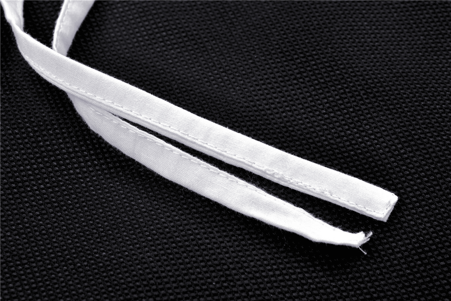 Close-up of white fabric straps on a black textured background, perfect for fashion detailing or dress customization.