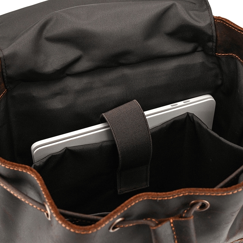 Inside view of a large genuine leather backpack with a laptop secured in a padded pocket.
